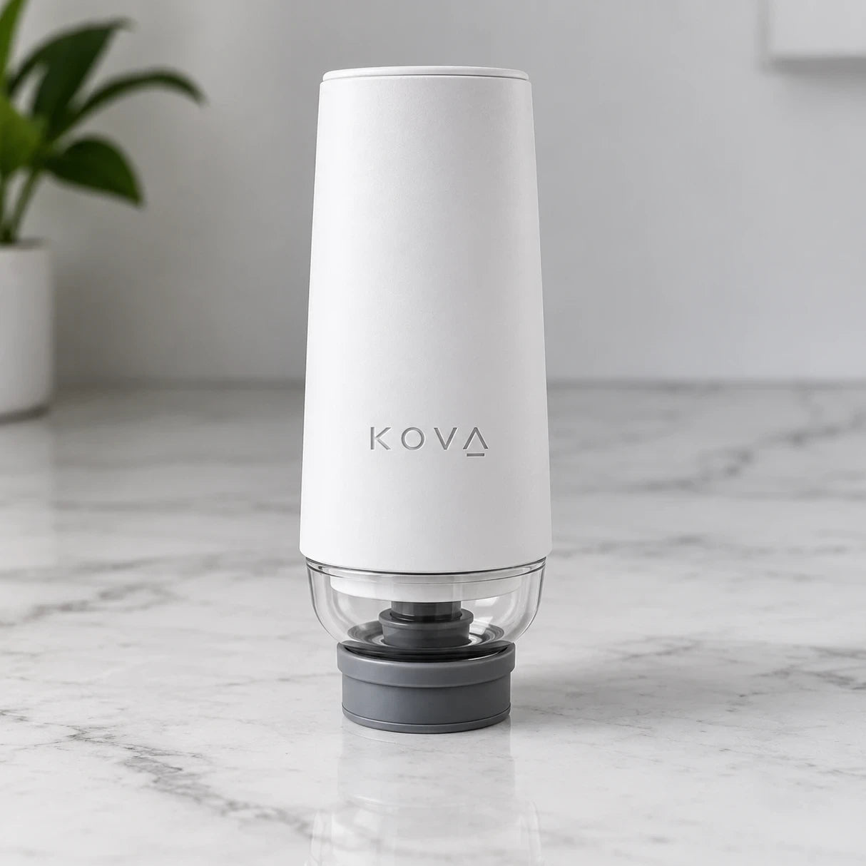 Kova Sealer, a white handheld vacuum sealer with a clear chamber, standing on a marble countertop